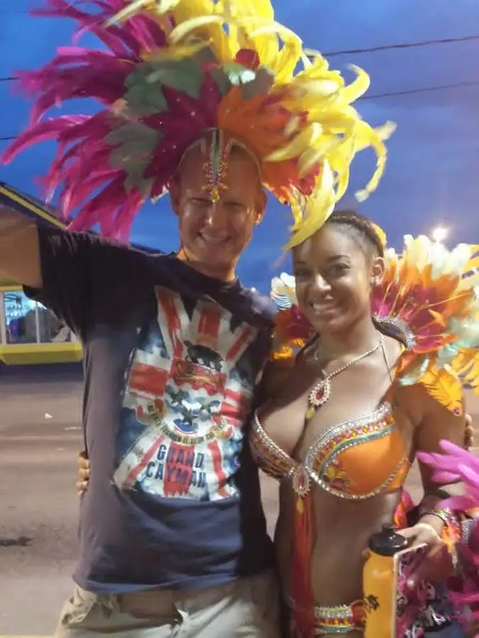 Me in a feathered carnival headdress next to a carnival dancer in Grand Cayman